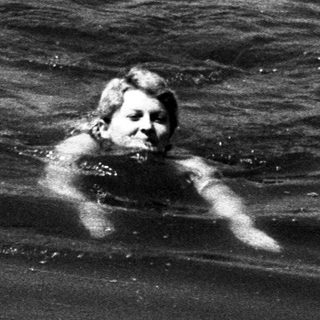 Black and white image of two people swimming in water.