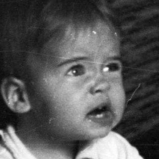 Baby sits on potty, holding a ball, looking distressed.