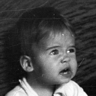 Baby sits on potty, holding a ball, looking distressed.