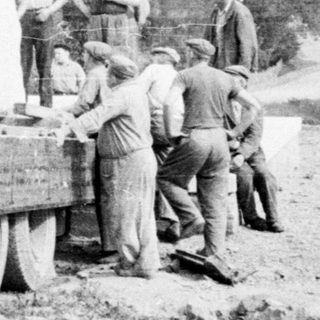 Men working near a truck unloading material outdoors.
