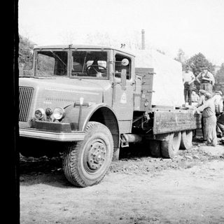 Men working near a truck unloading material outdoors.