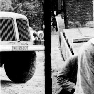 Men moving a large stone slab onto a wooden pallet.