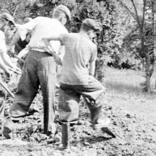 Men work outdoors, possibly constructing a road or embankment.