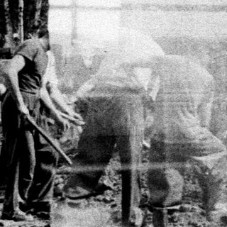 Men working a field with a tractor.
