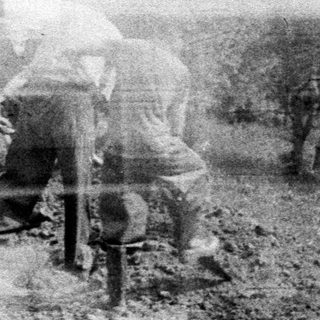 Men working a field with a tractor.