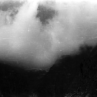 Dark, rocky terrain obscured by clouds and scratches.