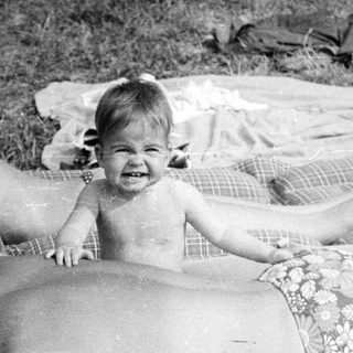 Family relaxing on a blanket in a grassy area.