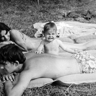 Family relaxing on a blanket in a grassy area.