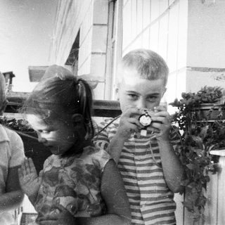 Three children looking at something with a vintage device.