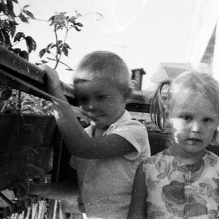 Three children pose outdoors in a vintage black and white photo.