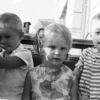 Three children pose outdoors in a vintage black and white photo.