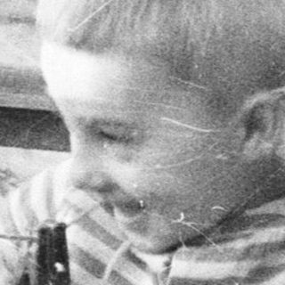 Three children play with a string on an outdoor balcony.