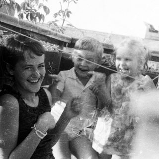 Four children smiling on a rooftop, black and white photo.