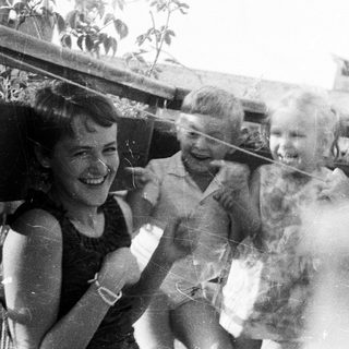Four children smiling on a rooftop, black and white photo.