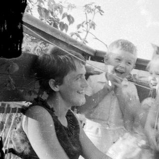 Here's a brief summary of the image: Three children smiling and posing outdoors.