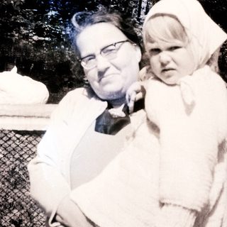 Man holding a baby outdoors, wearing a white garment.
