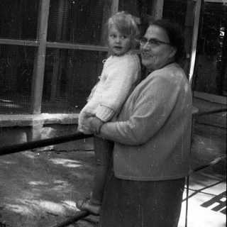 Woman holding a baby near an enclosure.