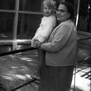 Woman holding a baby near an enclosure.