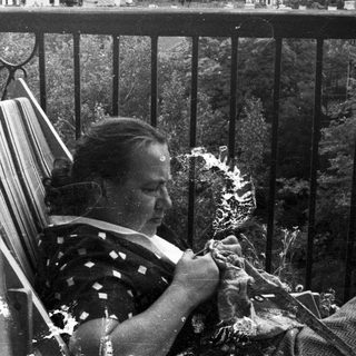 Woman knitting on a porch, seated in a rocking chair.