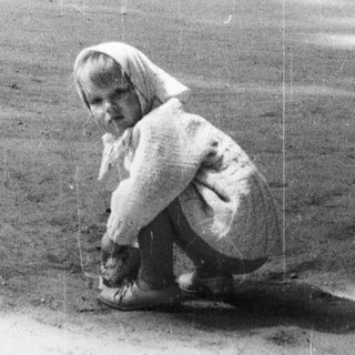 Child crouches near an elephant enclosure in a zoo.