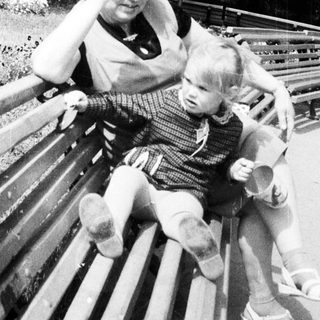Woman and child sit on a park bench together.