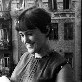Woman smiles with a building reflected in the background.