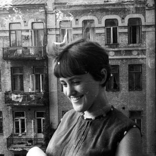 Woman smiles with a building reflected in the background.