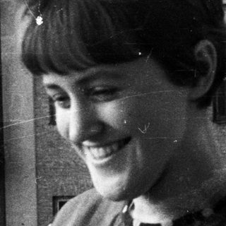 Woman smiles with a building reflected in the background.