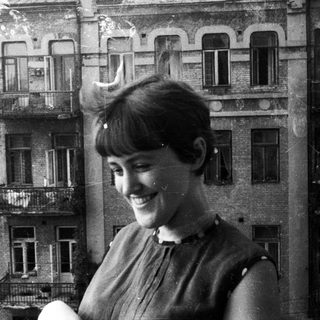 Woman smiles with a building reflected in the background.
