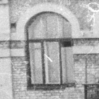Woman smiles with a building reflected in the background.