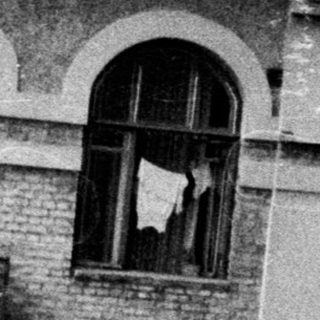 Man stands near building, looking off to the side.