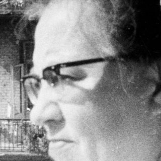 Woman stands on a balcony, overlooking a building.