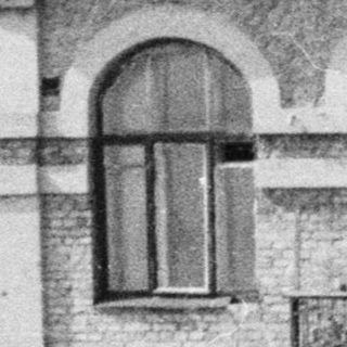 Woman stands on a balcony, overlooking a building.