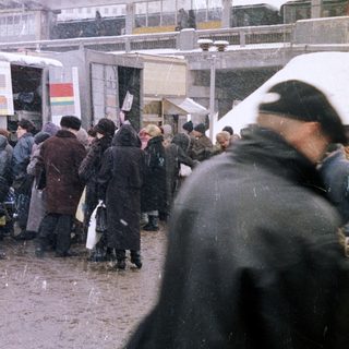 Crowded market scene with snow falling and a train station.