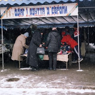 Outdoor market stall with vendors and customers in winter.