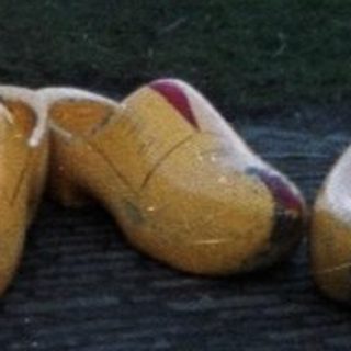 People walk along a canal with wooden shoes.