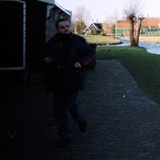 People walk along a canal with wooden shoes.