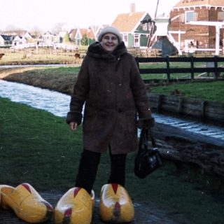 People walk along a canal with wooden shoes.