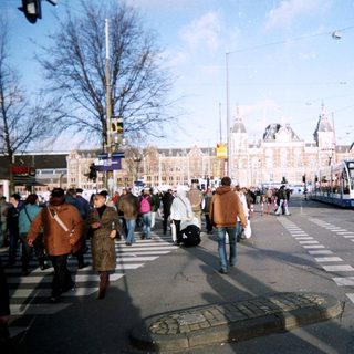 People crossing street near a train station building.