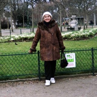 Person stands near Eiffel Tower in a park.