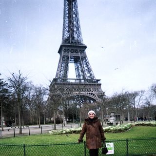 Person stands near Eiffel Tower in a park.