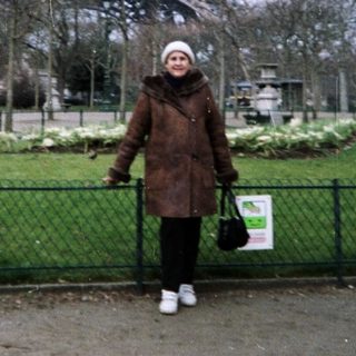 Person stands near the Eiffel Tower in a park.
