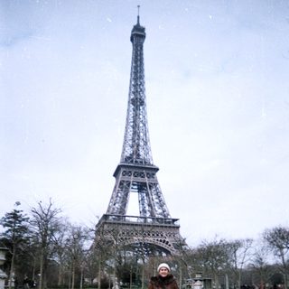 Person stands near the Eiffel Tower in a park.