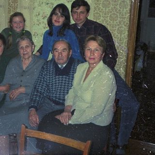 Family portrait indoors, with elderly relatives and younger generations.