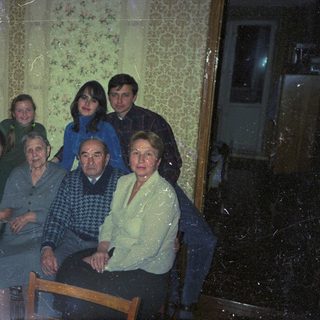 Family portrait indoors, with elderly relatives and younger generations.