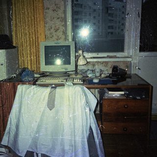 Dimly lit room with old computer and dresser.