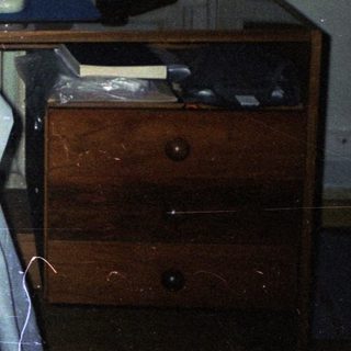 Dimly lit room with old computer and dresser.