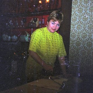 Man in yellow shirt stands in a patterned room.