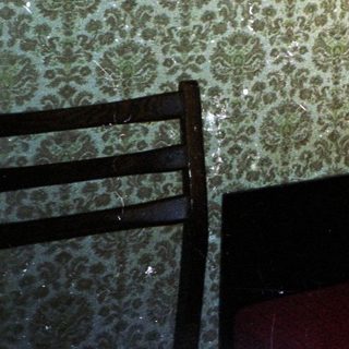 Man sits on a red couch in a patterned room.