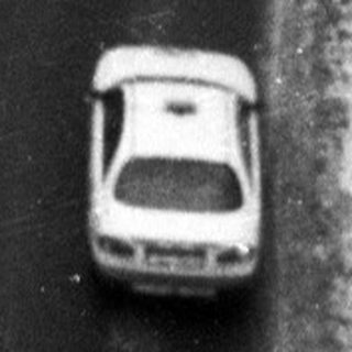 Car driving on a snowy road through a forest.